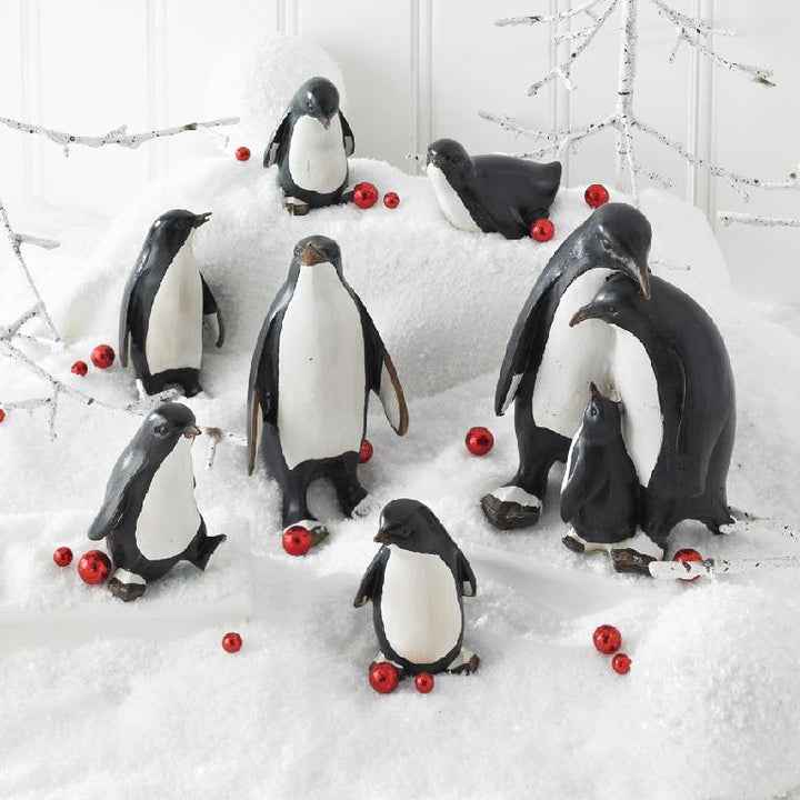 Penguin figurines with red berries on a snowy background