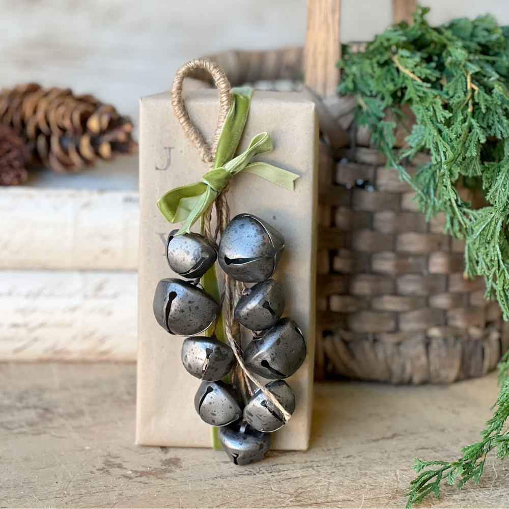 Pewter metal bells drop and green ribbon on a gift box
