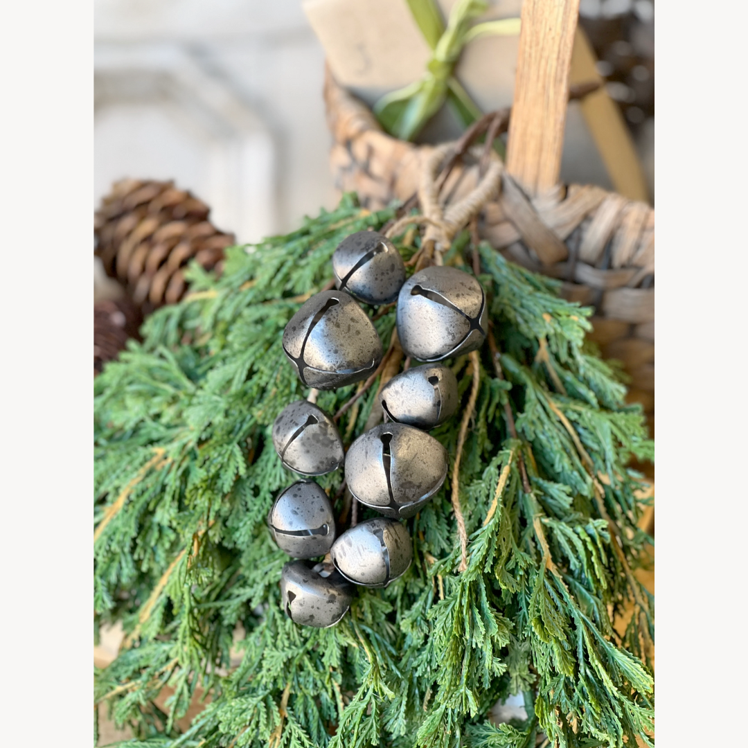 Decorative wreath with metallic jingle bells and pine cones on a white background