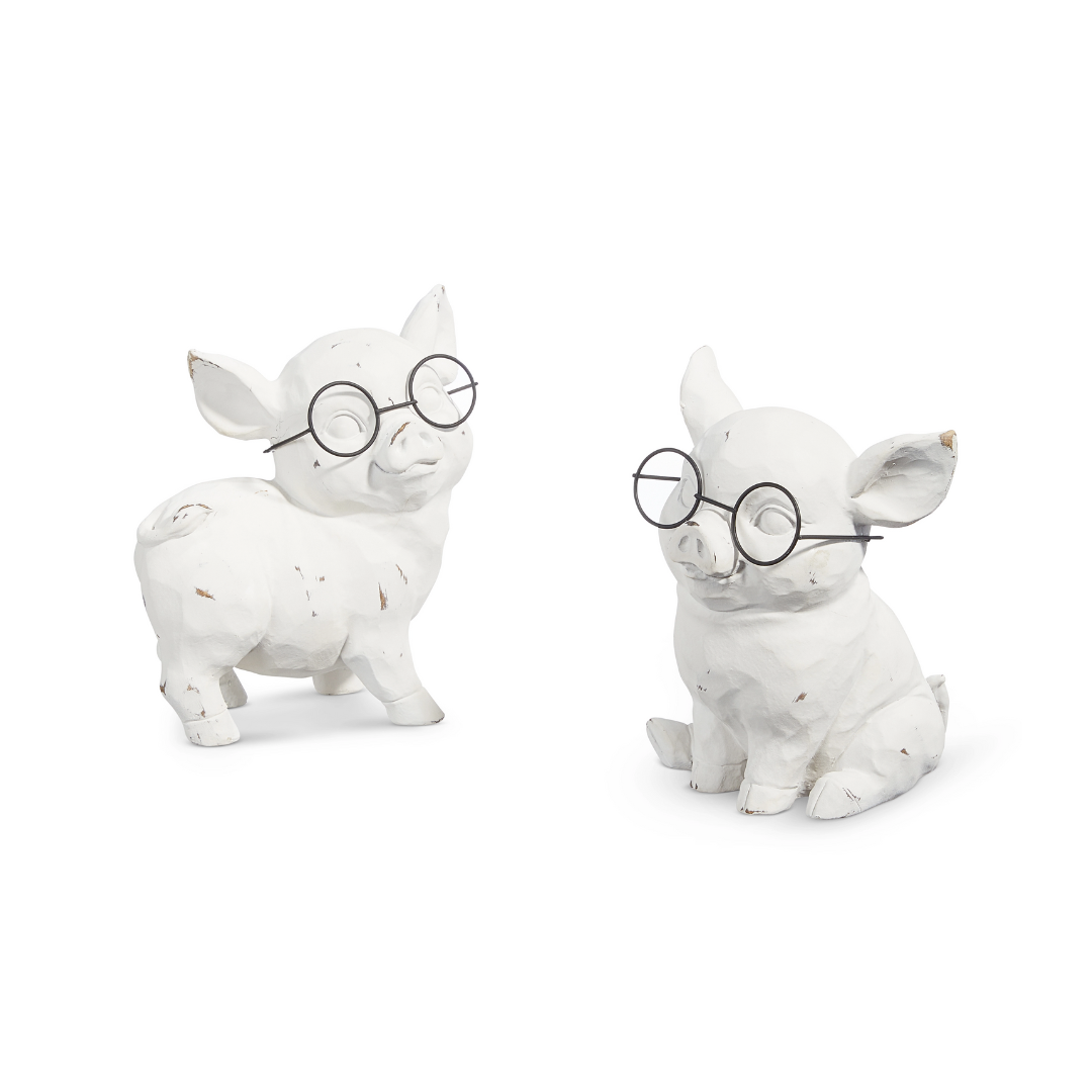 Two white ceramic pig figurines wearing glasses on a white background