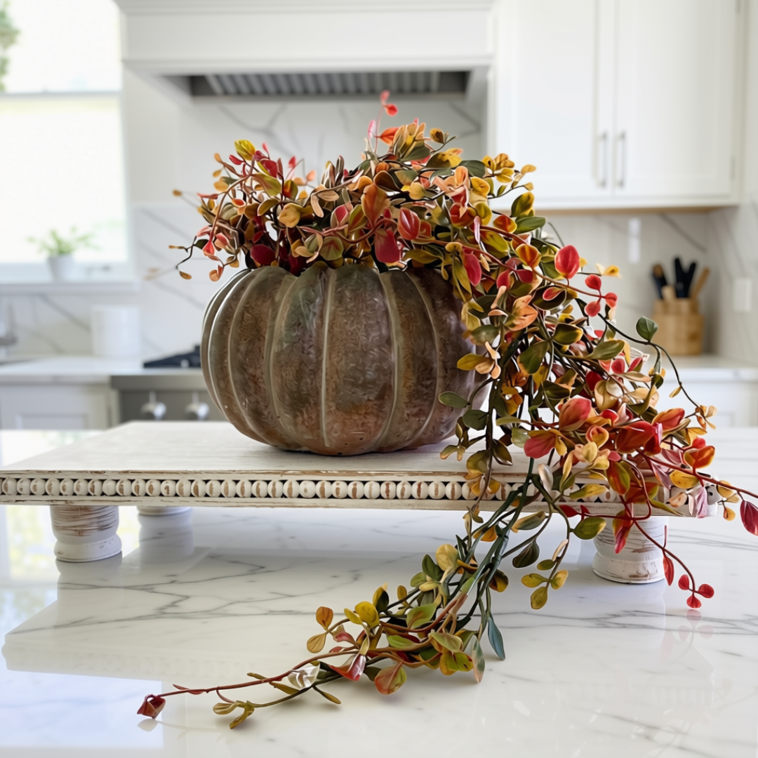 A hanging vine of artificial greenery in red, yellow, and green colors, displayed in a terracotta pot, intended for fall decor.