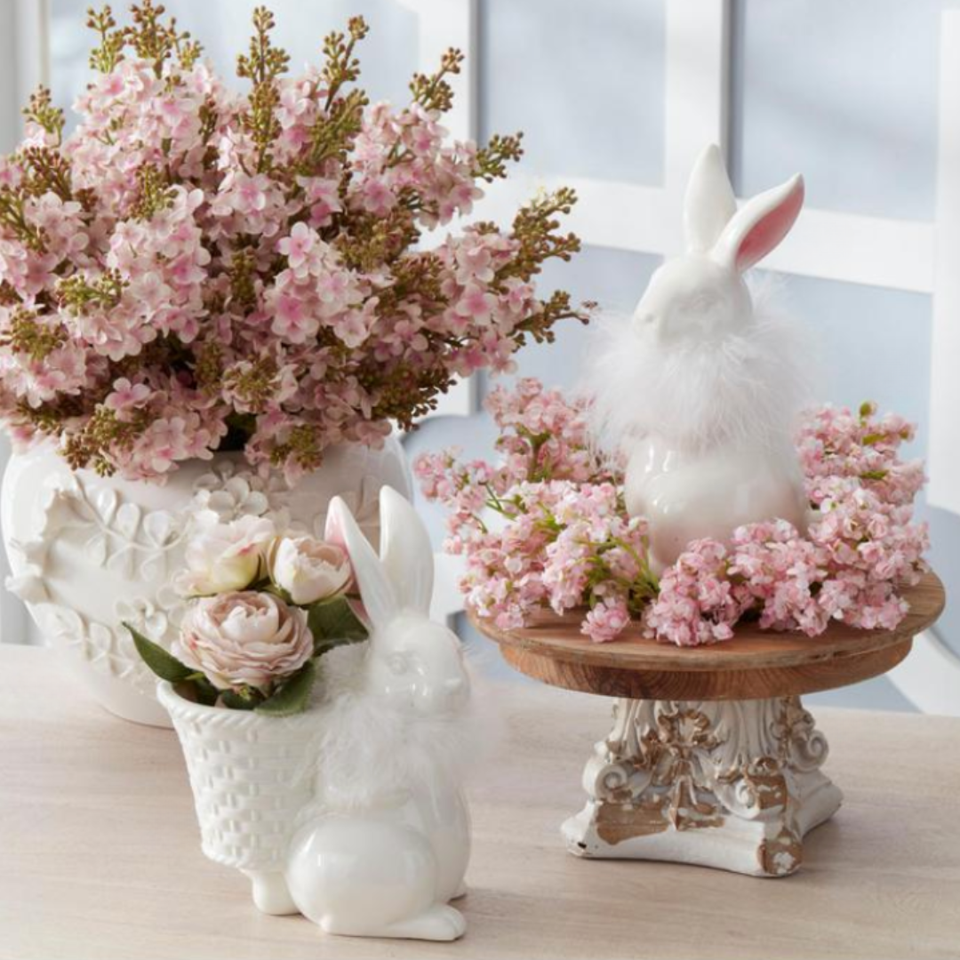 Decorative items including a rabbit-shaped vase, a rabbit figurine, and a small table with pink flowers on a light background.