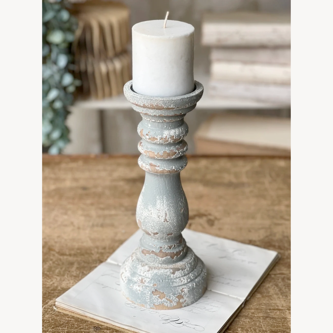 Decorative candle holder with a white candle on a wooden surface