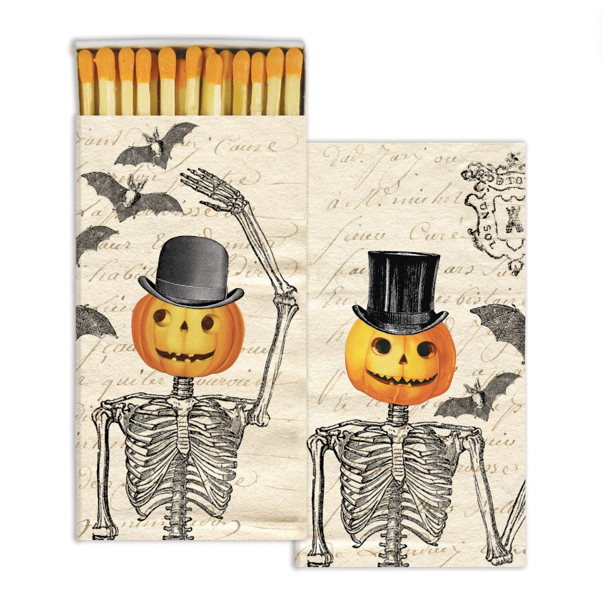 A matchbox with a Halloween-themed design featuring a pumpkin and skeleton, on a white background.