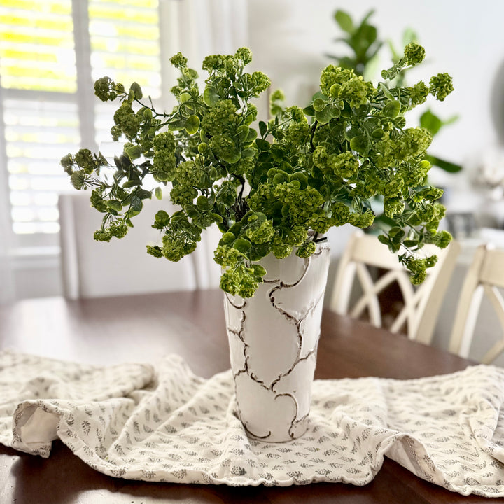 Green real touch flowers in a white vase on a wooden table with a white cloth