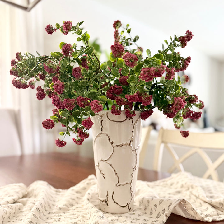 Decorative vase with purple flowers on a table with a blurred background