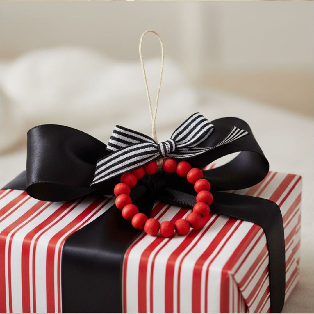 Red beaded ornament with a black and white striped bow on a red and white striped gift box.