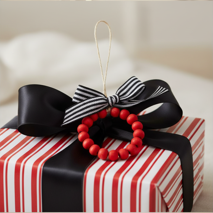 Red beaded ornament with a black and white striped bow on a red and white striped gift box.