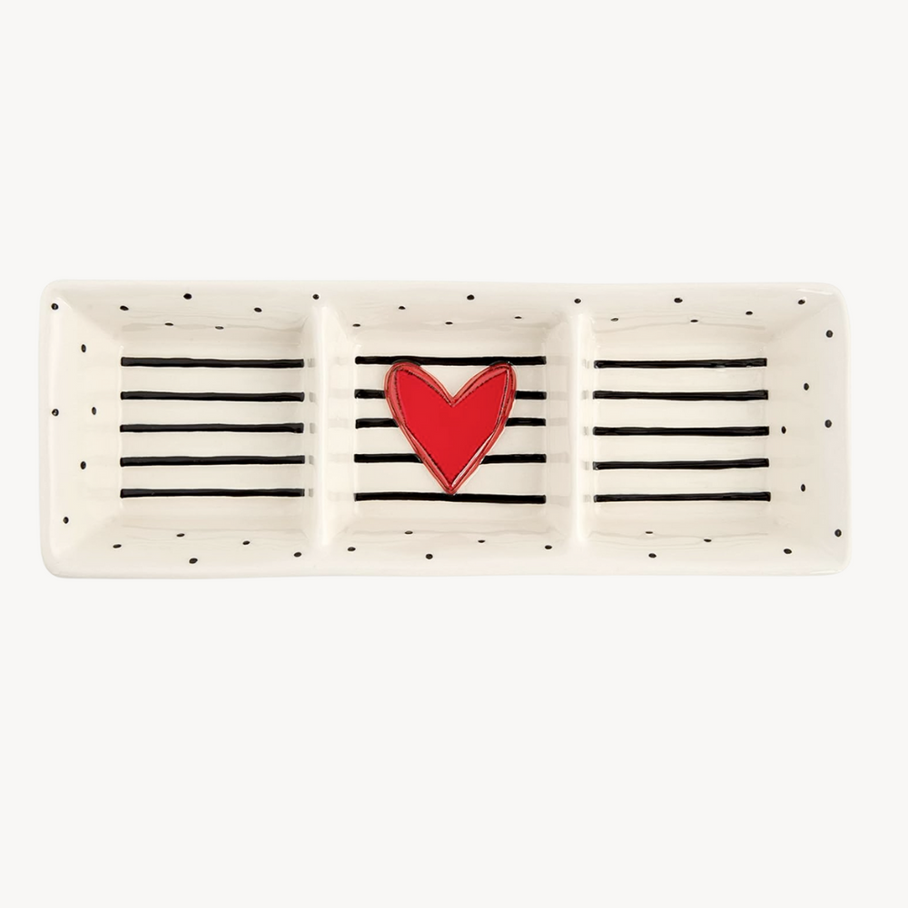 A divided stoneware serving dish with a white speckled background and a red heart shape in the center, with black horizontal stripes.