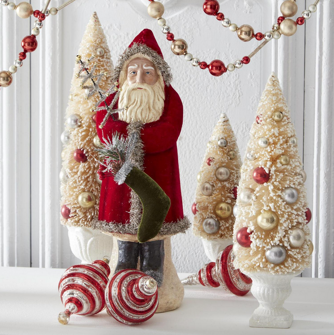Decorative Christmas scene with Belsnickle Santa figure and trees on a white surface.