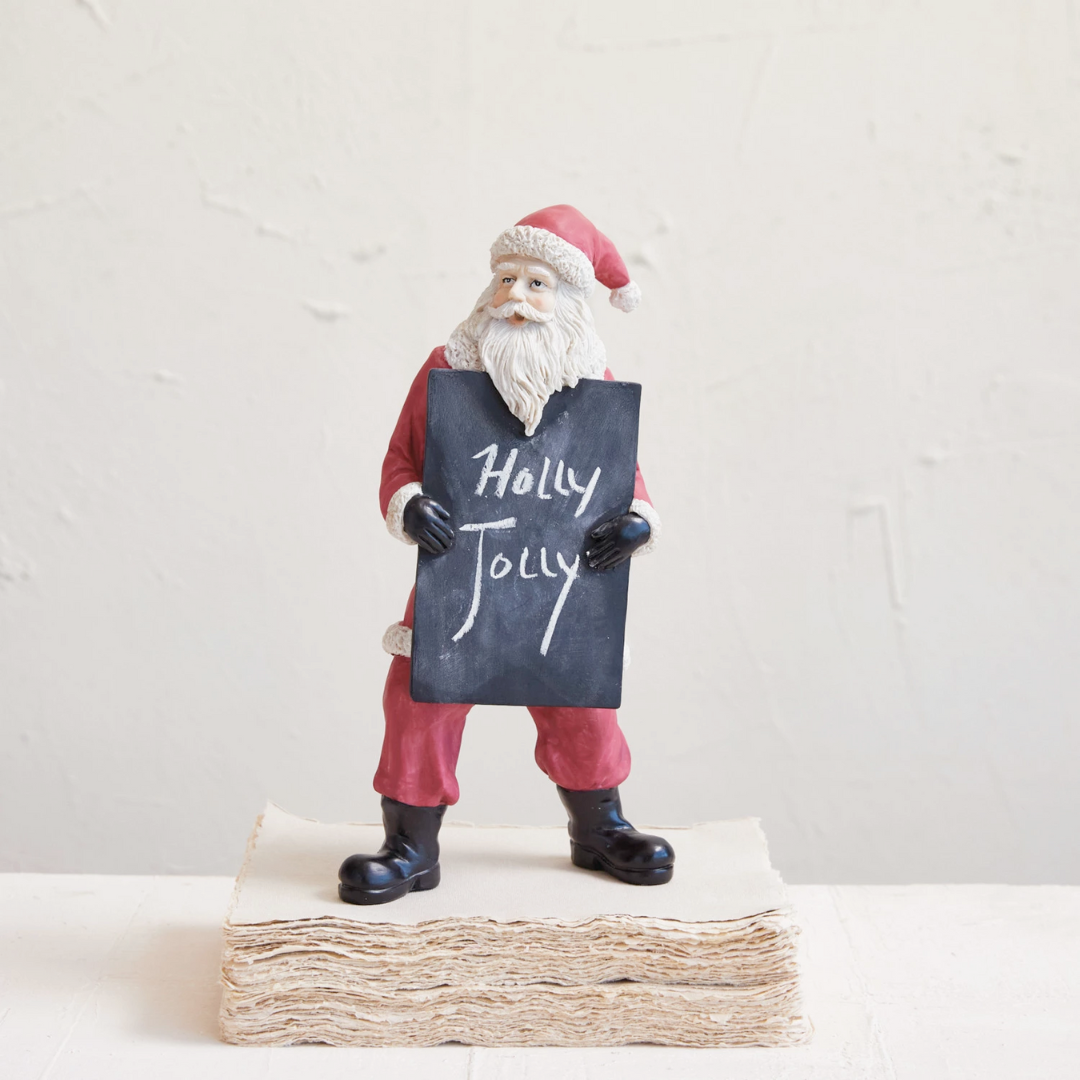 A vintage inspired Santa With Chalkboard decoration, featuring a resin Santa figure in red and white holding a chalkboard with the text 'Welcome + Merry Christmas'.