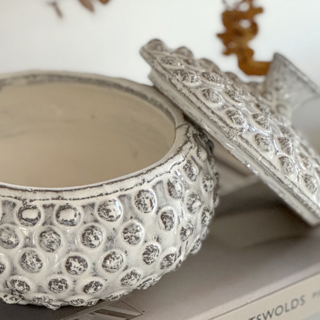 Decorative white ceramic container with textured surface on a white background