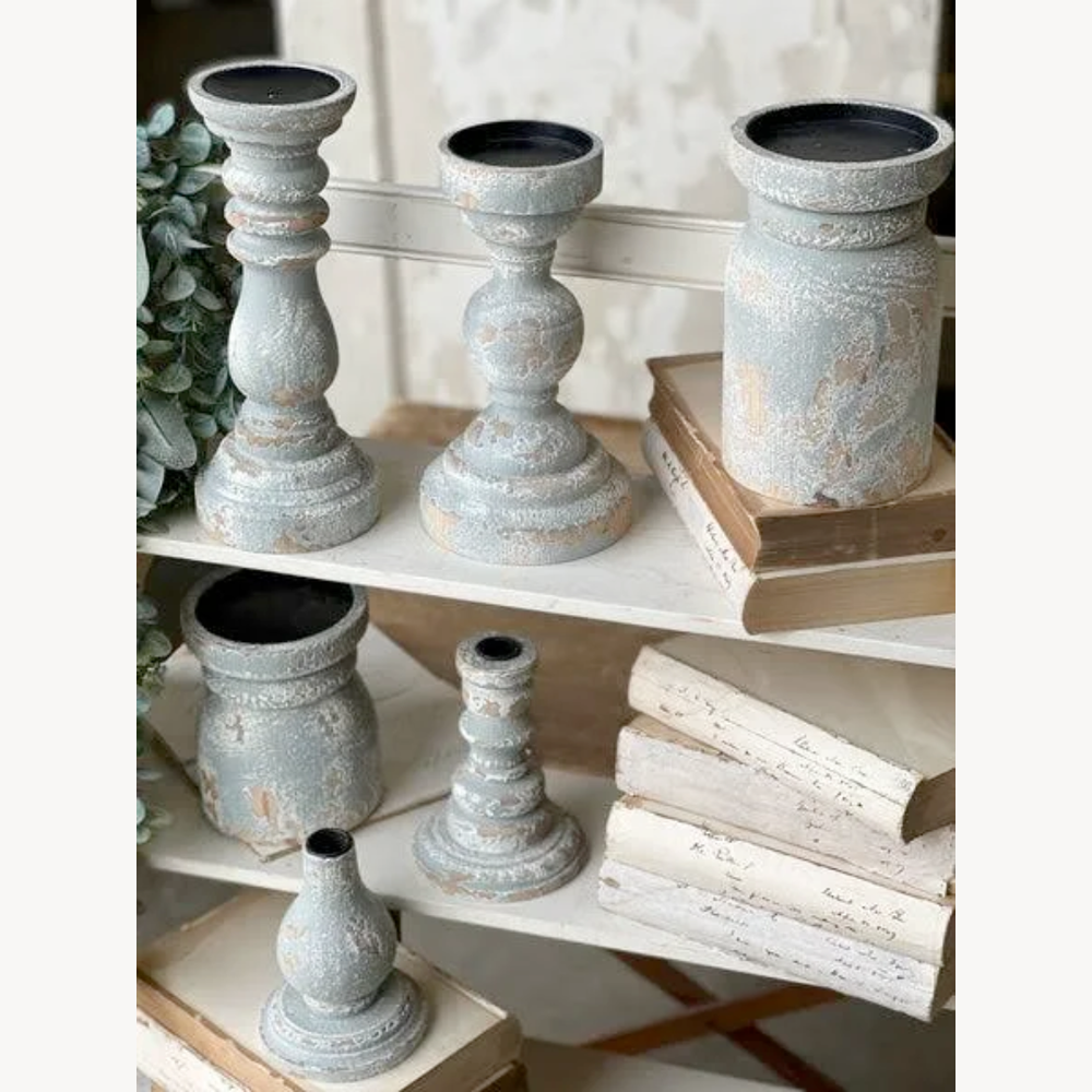 Set of rustic candle holders on a shelf with books and decorative items.
