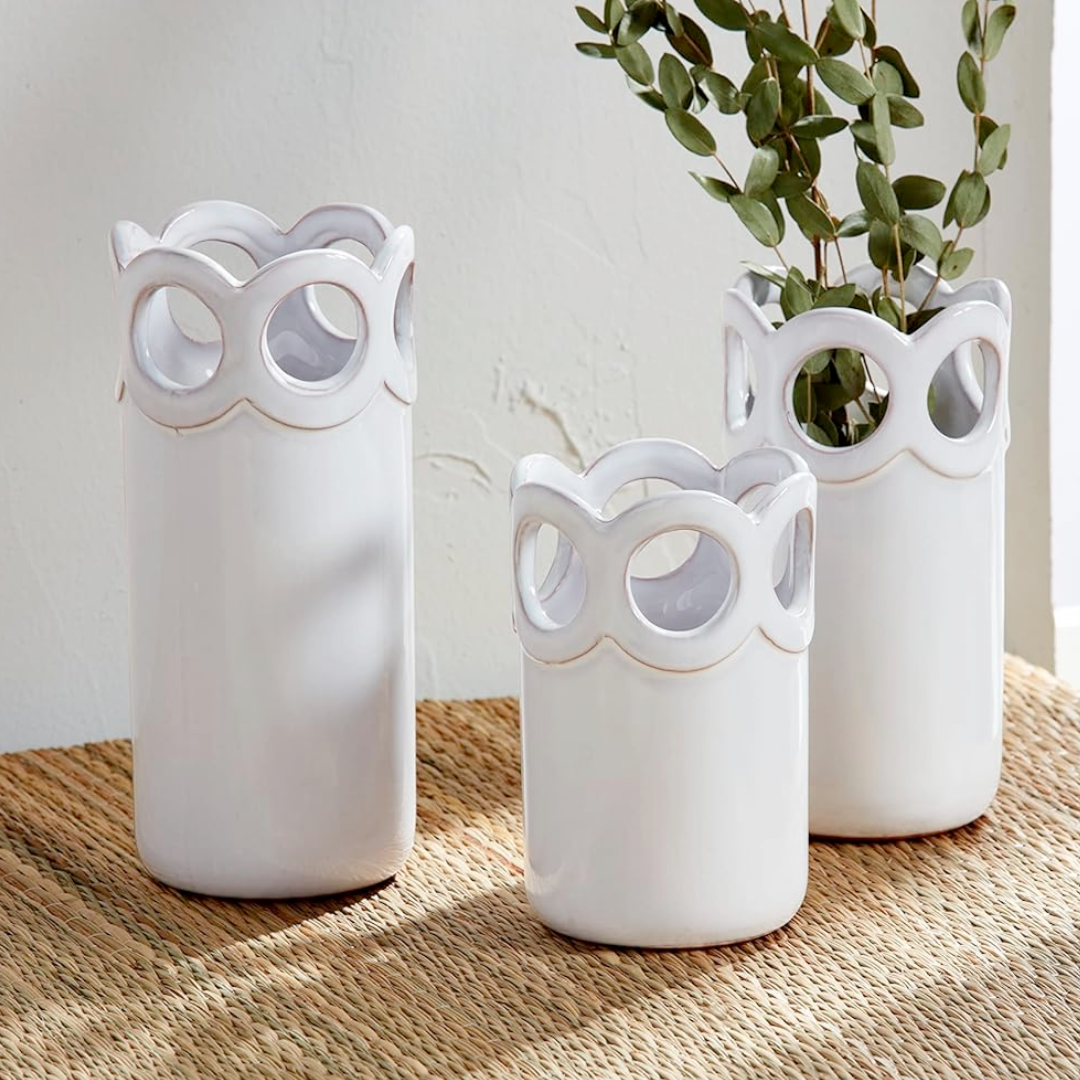 Three white terracotta bud vases with scalloped edge design, displayed on a woven surface. Each vase has cut-out scallop detailing and is in different sizes.