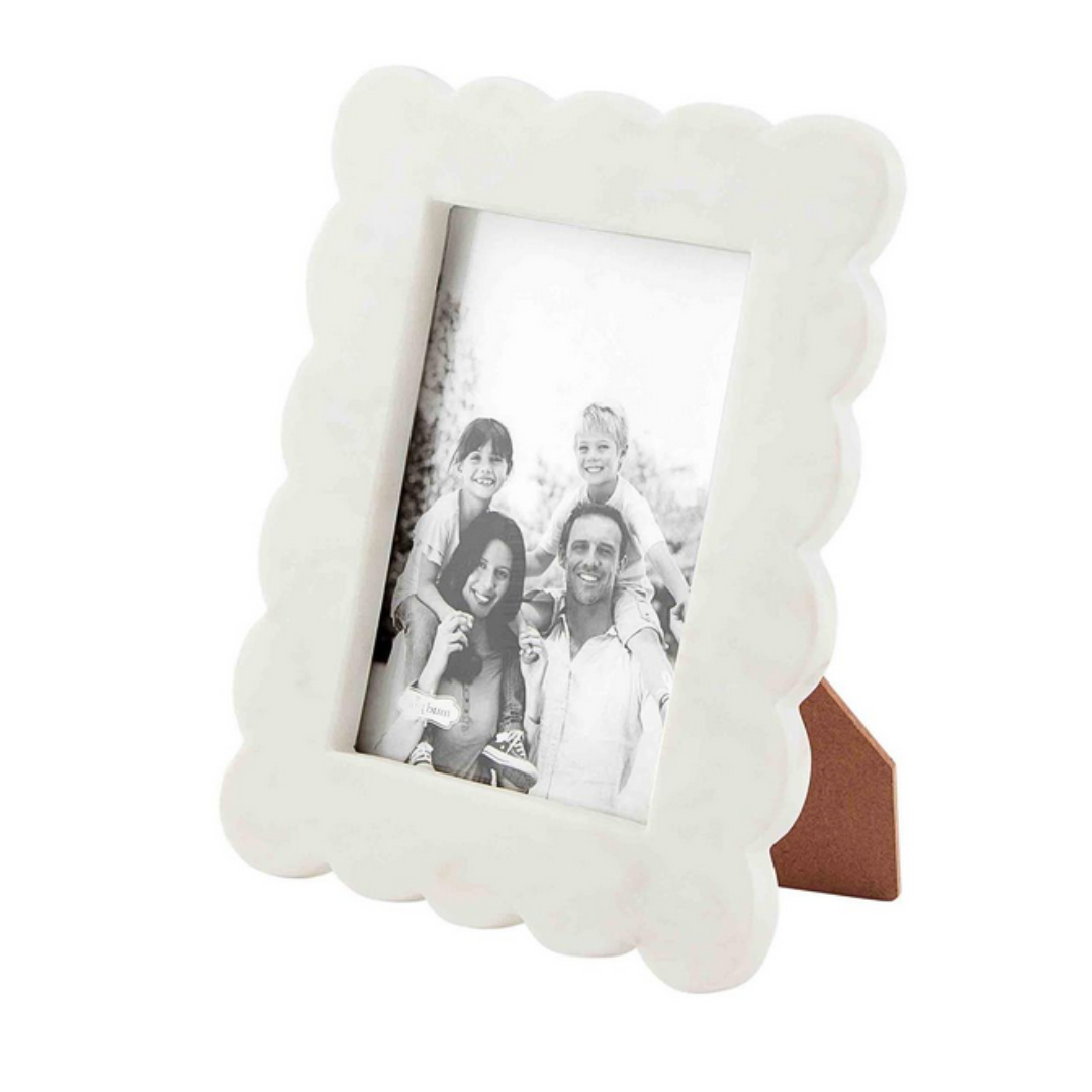 White scalloped photo frame with a family photo inside on a white background