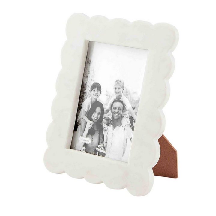 White scalloped photo frame with a family photo inside on a white background