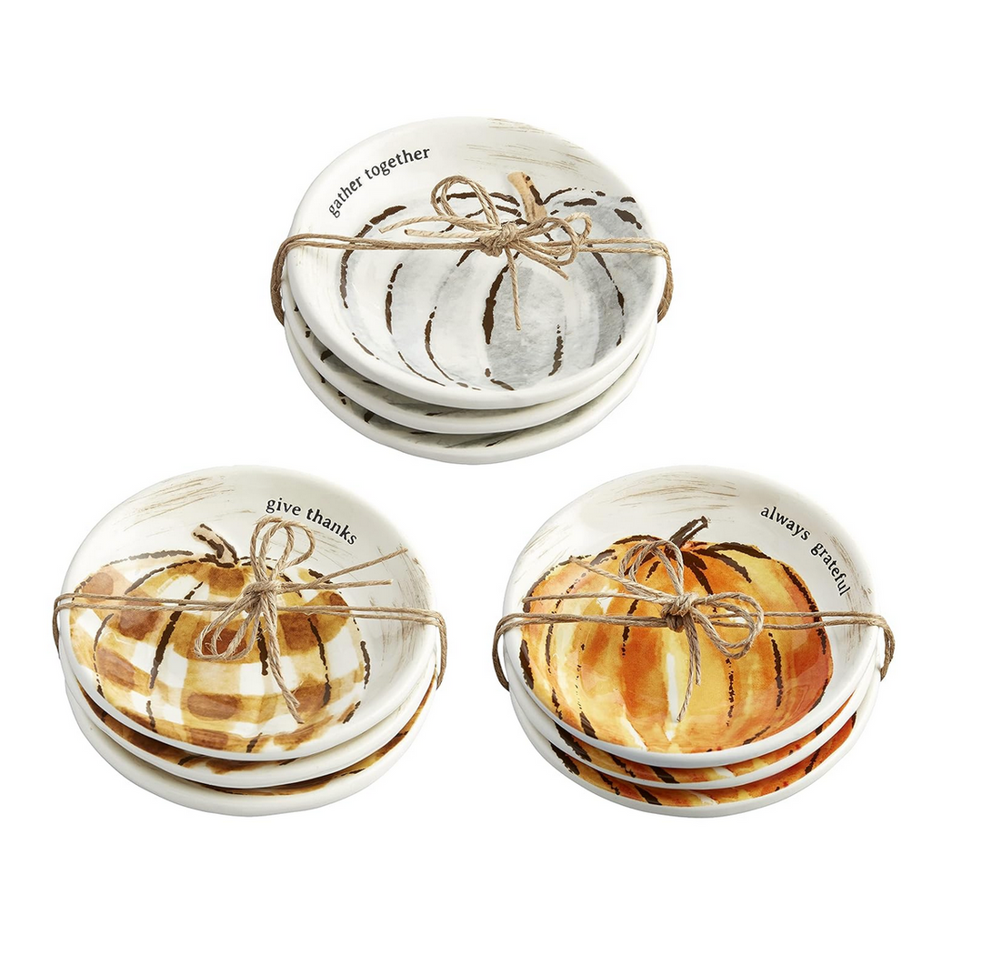 Set of four Thanksgiving ceramic dishes with pumpkin designs and text on a white background