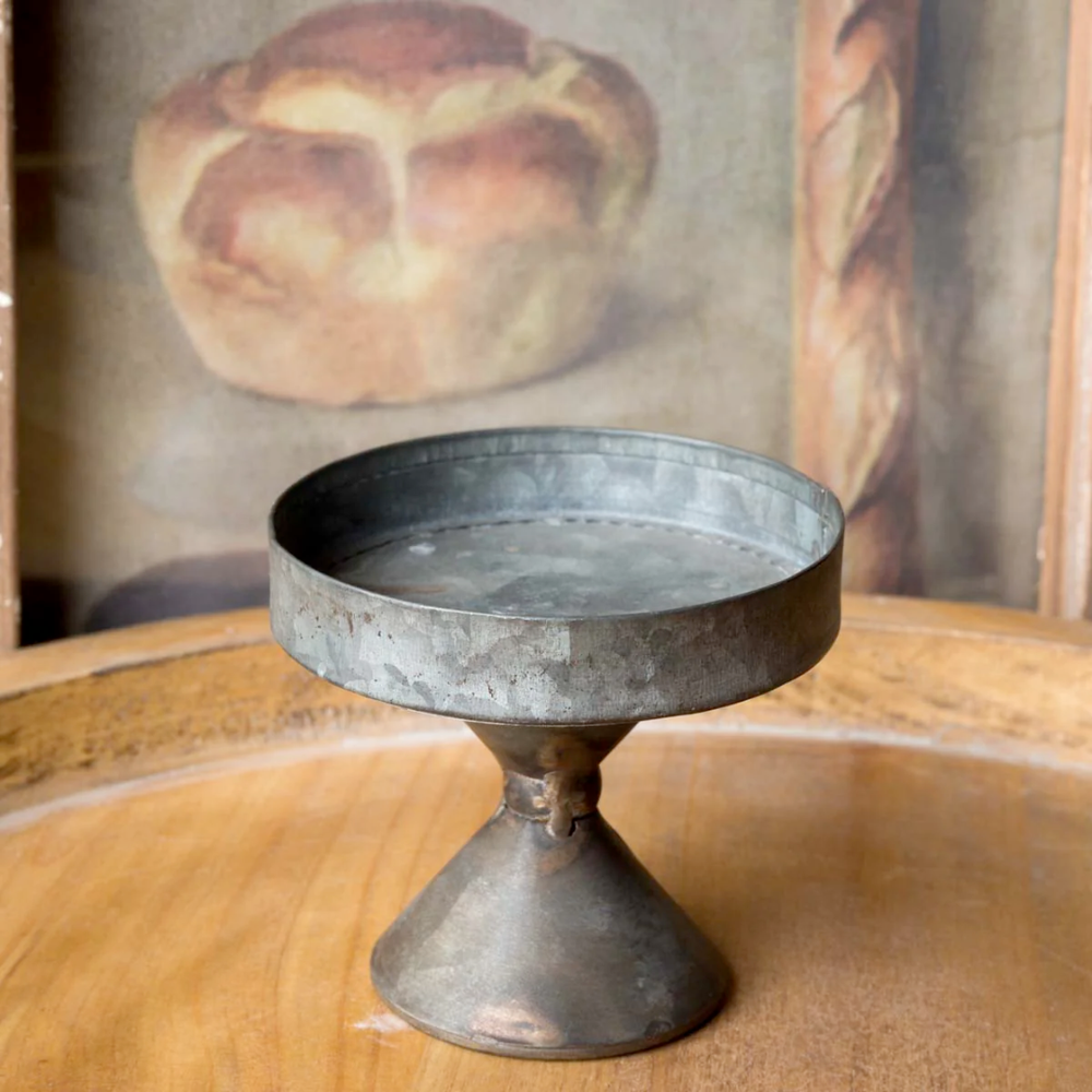 Metal pedestal dish on a wooden surface with a blurred background