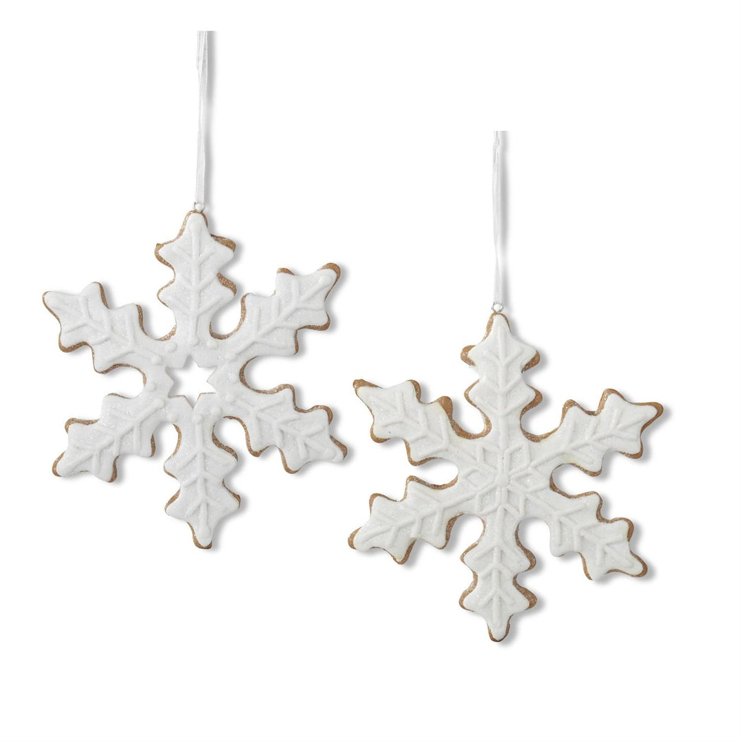 Two white gingerbread snowflake ornaments on a white background