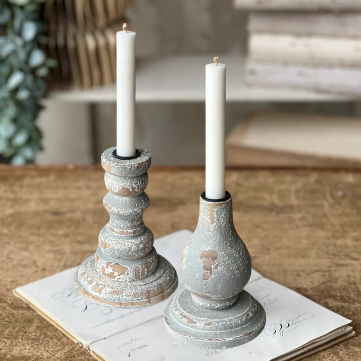 Two candle holders with candles on a rustic surface