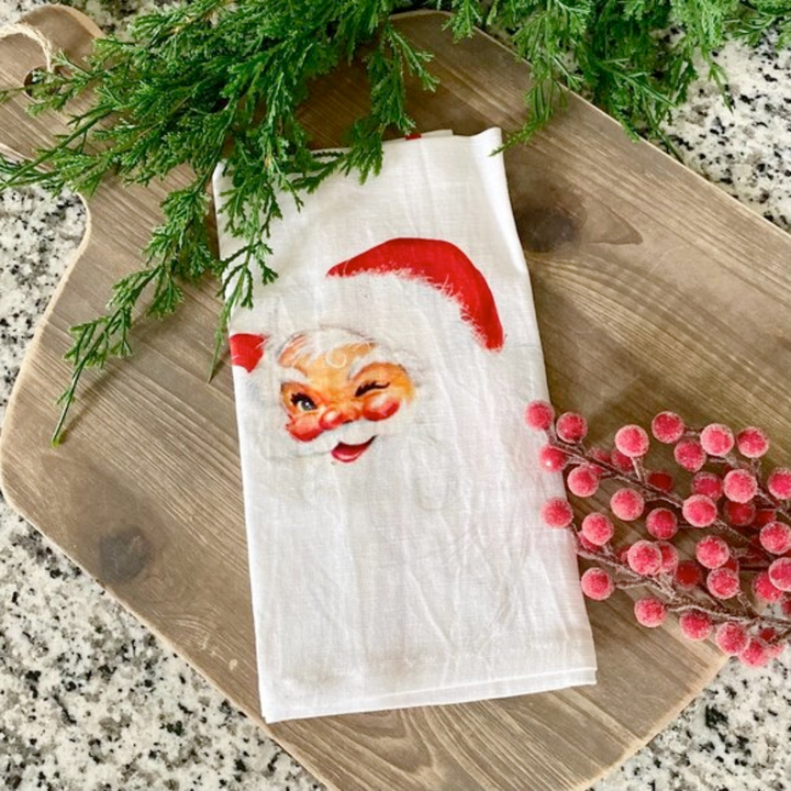 Napkin with Santa Claus design on a wooden board with greenery and berries