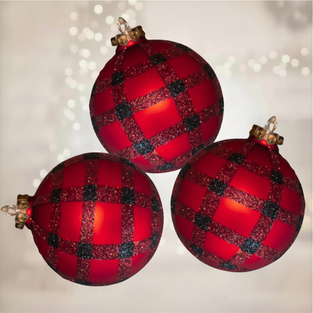 Three red and black checkered Christmas ornaments on a blurred light background