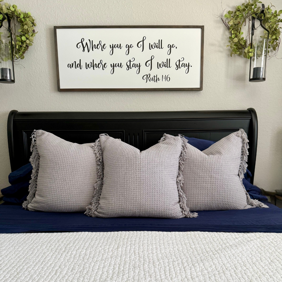 Bedroom with gray pillows and a framed quote above the bed