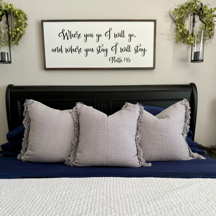 Bedroom with gray pillows and a framed quote above the bed