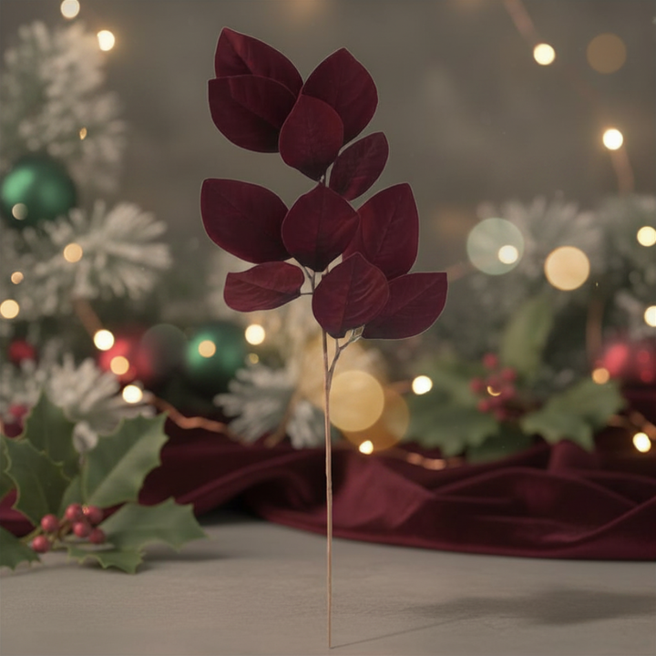 Decorative burgundy leaf stem with green holly leaves and berries on a blurred light background.