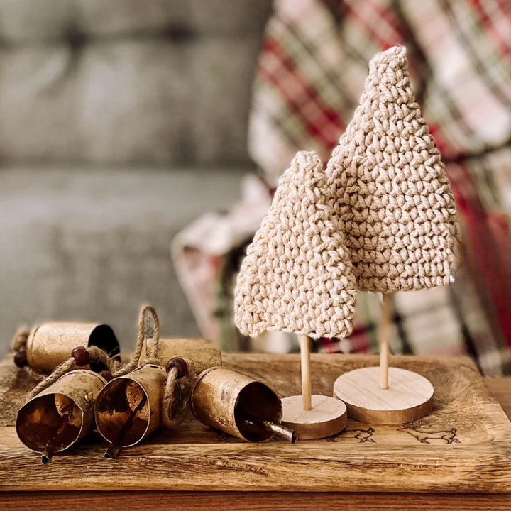 Crocheted Christmas trees and bells on a wooden surface with a blurred background
