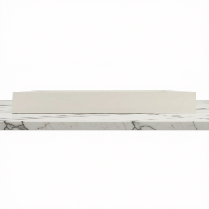 A rectangular white tray with a smooth matte finish, shown from a side angle resting on a white marble surface with gray veining against a white background.