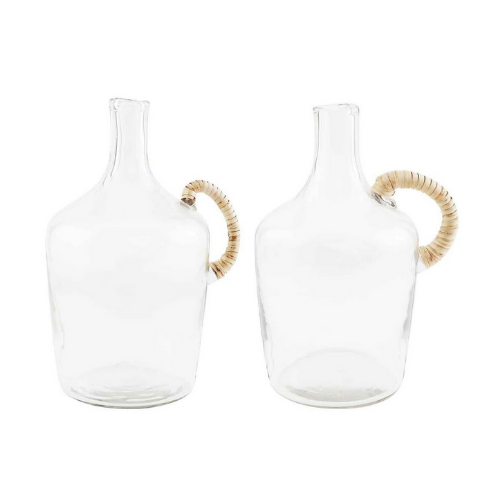 Two clear glass carafes with woven handles on a white background
