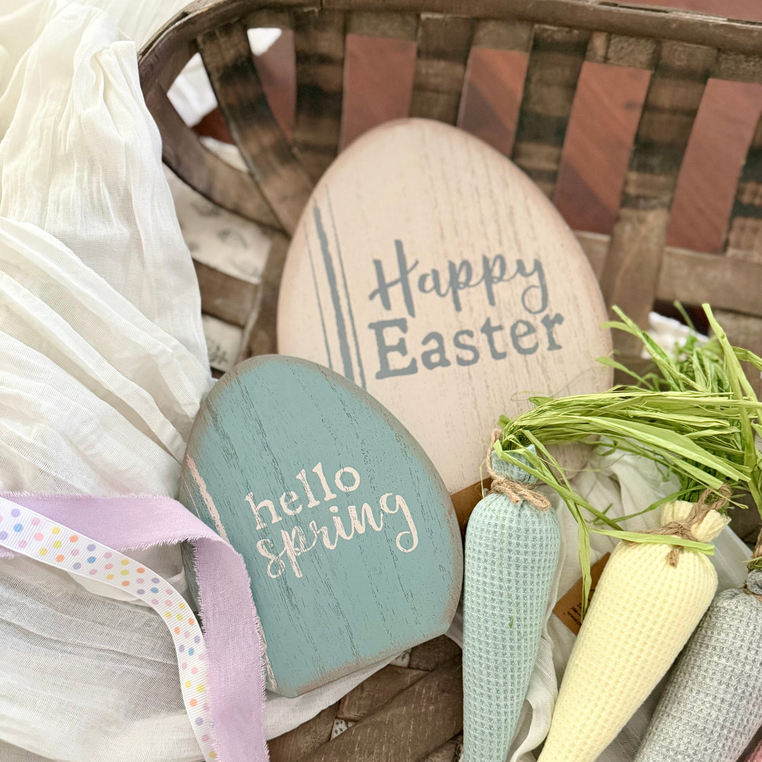 Decorative Easter eggs with 'Happy Easter' and 'hello spring' text, surrounded by a basket and decorative carrots.