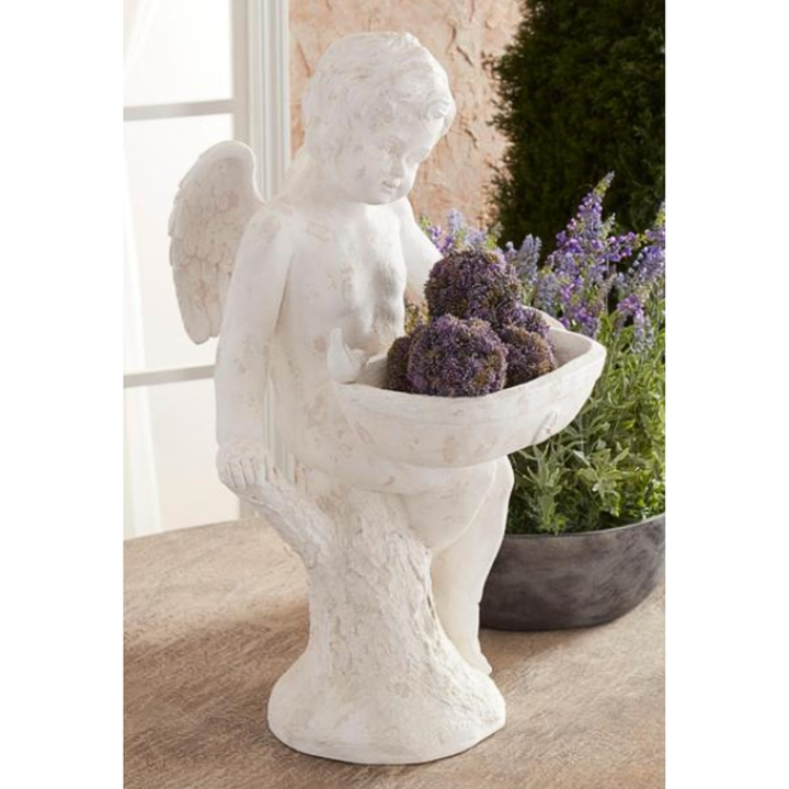 Statue of an angel holding flowers in a garden setting