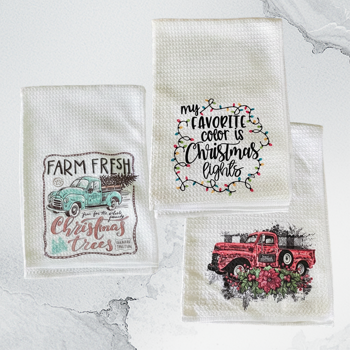 Three decorative towels with Christmas-themed designs on a marble surface.