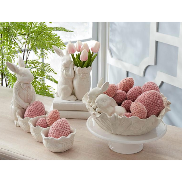 Decorative Easter scene with ceramic bunnies and crocheted eggs on a table.