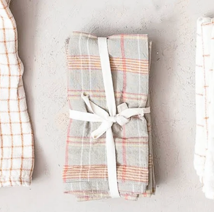 Folded plaid cotton napkins with a white ribbon on a light gray background