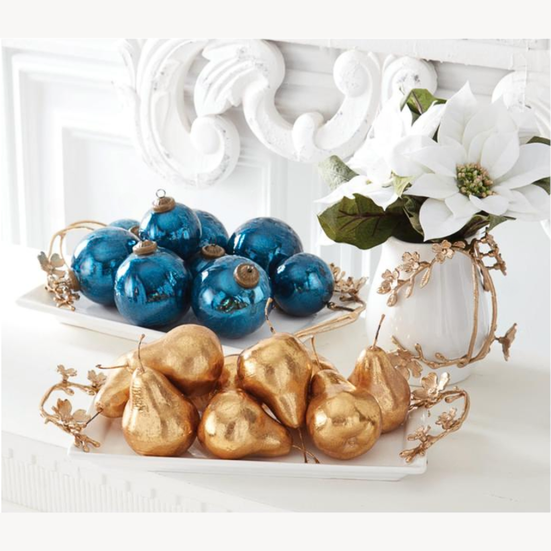 Decorative display with blue ornaments and gold metallic pears on a white surface.