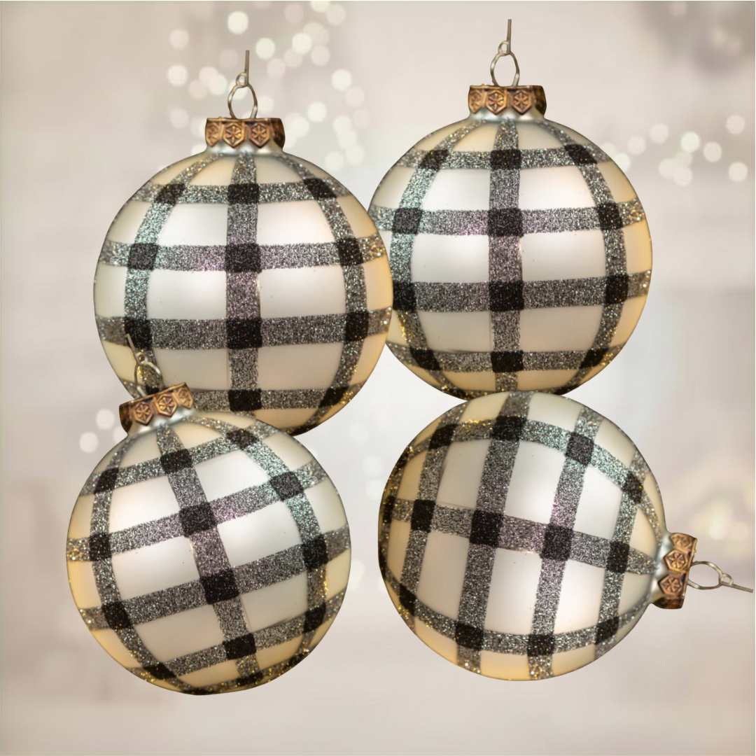 Four glass ornaments with black and white checkered pattern on a soft background