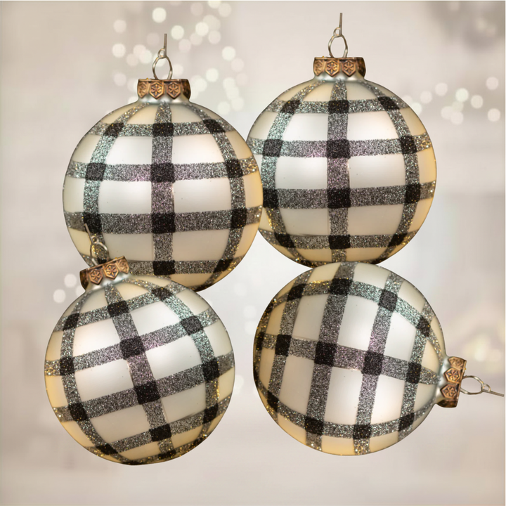 Four glass ornaments with black and white checkered pattern on a soft background
