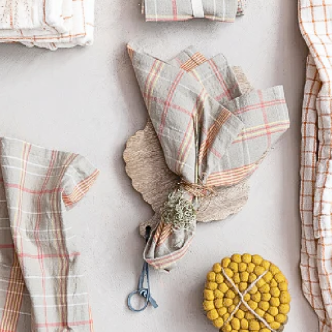 A set of woven cotton plaid napkins in taupe, orange and cream checkered pattern