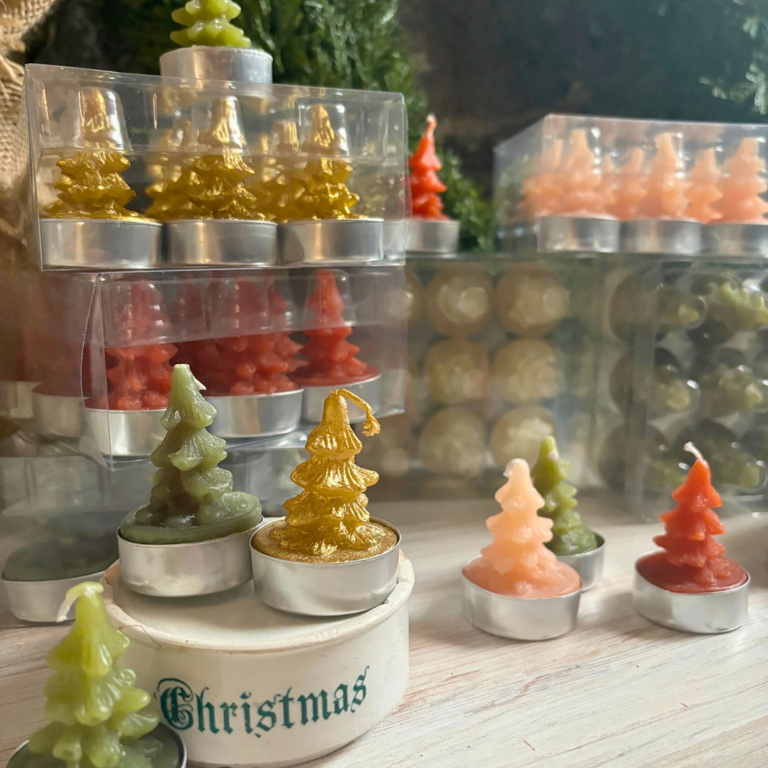 Stacked display of Christmas-themed candles in various shapes and colors on a wooden surface.