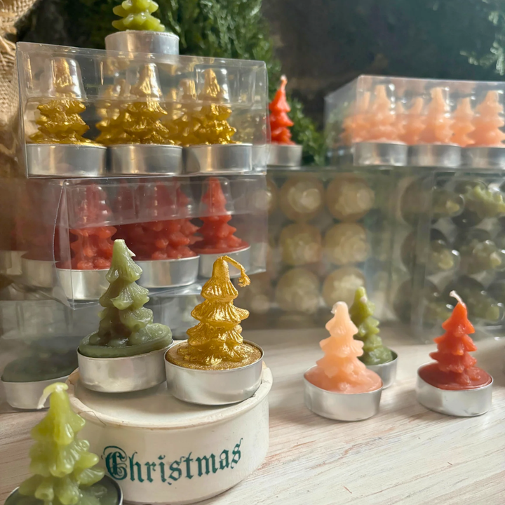 Stacked display of Christmas-themed candles in various shapes and colors on a wooden surface.