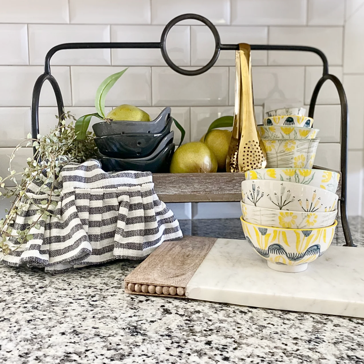 Kitchen counter with bowls, a towel, and apples against a tiled wall.