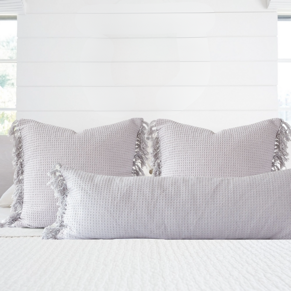 Gray textured pillows with tassels on a white bed