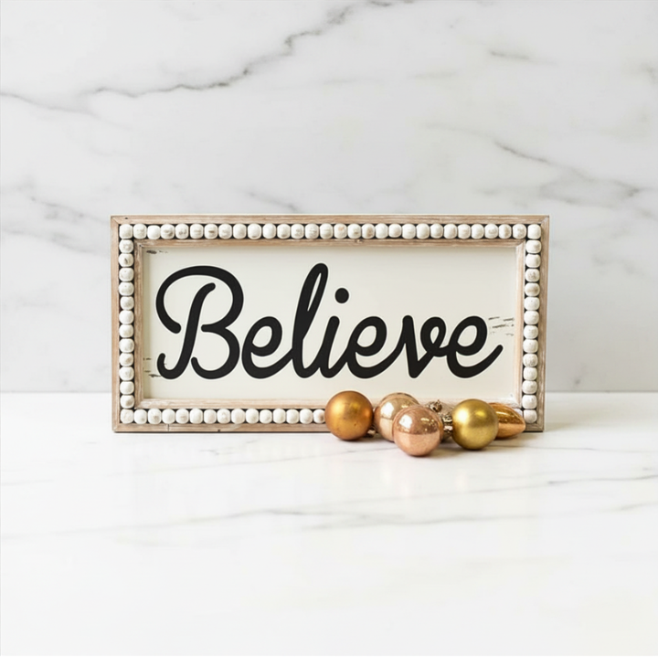 Decorative sign with 'Believe' text on a marble background