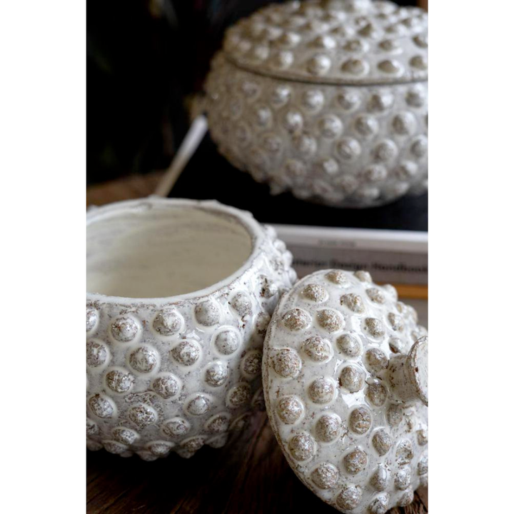 White textured ceramic pots with lids on a wooden surface
