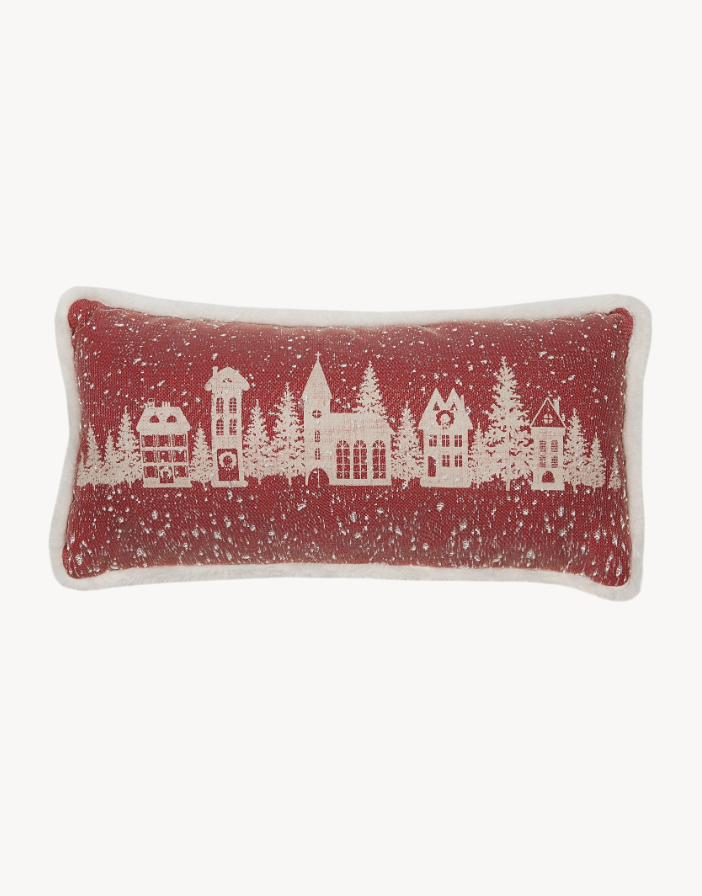 Decorative pillow with a winter village design on a red background