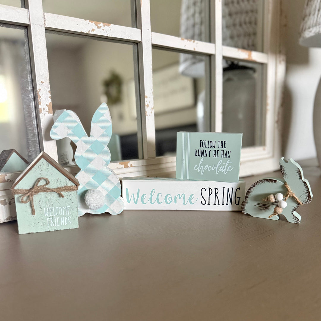 Decorative items including a bunny, house, and sign with 'Welcome Spring' on a surface.