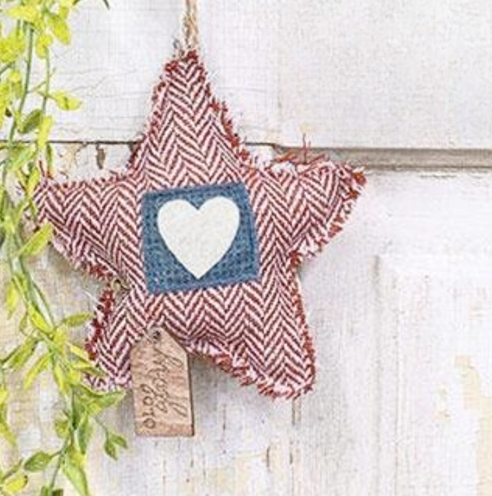 Star-shaped decorative item with a heart in the center, hanging on a white wooden surface.